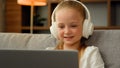 Beautiful kid child little gamer studying online on laptop at home listen audio music in headphones playing computer Royalty Free Stock Photo
