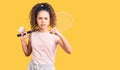 Beautiful kid girl with curly hair holding badminton racket and shuttlecock annoyed and frustrated shouting with anger, yelling Royalty Free Stock Photo