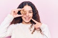 Beautiful kid girl with curly hair holding cookie smiling happy pointing with hand and finger Royalty Free Stock Photo