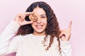 Beautiful kid girl with curly hair holding cookie smiling happy pointing with hand and finger to the side Royalty Free Stock Photo
