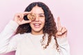 Beautiful kid girl with curly hair holding cookie smiling with an idea or question pointing finger with happy face, number one Royalty Free Stock Photo