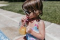 Beautiful kid girl at the pool drinking healthy orange juice and having fun outdoors. Summertime and lifestyle concept Royalty Free Stock Photo