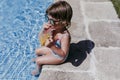 beautiful kid girl at the pool drinking healthy orange juice and having fun outdoors. Summertime and lifestyle concept Royalty Free Stock Photo