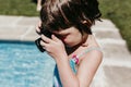 Beautiful kid girl taking a picture with old vintage camera in a pool. Smiling. Fun and summer lifestyle Royalty Free Stock Photo