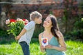 Beautiful kid and mom in spring park, flower and present. Mother getting gift from toddler boy for Mothers day Royalty Free Stock Photo