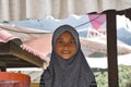 A beautiful, kind and innocent young Malaysian muslim girl in traditional hijab smiling and helping her mother selling goods in a