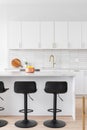 A kitchen detail with white cabinets, gold faucet and black bar stools. Royalty Free Stock Photo