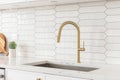 A kitchen detail with white cabinets, gold faucet, and tiled backsplash. Royalty Free Stock Photo