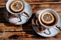 Beautiful kitchen set for a tea ceremony for two people. Two white ceramic tea cups on saucers on a wooden table. Black tea with Royalty Free Stock Photo