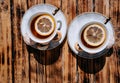 Beautiful kitchen set for a tea ceremony for two people. Two white ceramic tea cups on saucers on a wooden table. Black tea with Royalty Free Stock Photo