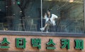 Beautiful Korean girl sitting at the table in the Starbucks cafe. Smartphone in hand