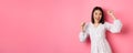 Beautiful korean woman dancing and having fun, smiling happy at camera, posing against pink background Royalty Free Stock Photo