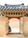 Beautiful Korean woman dressed Hanbok passing the traditional door in palace. Royalty Free Stock Photo