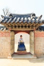 Beautiful Korean woman dressed Hanbok passing the traditional door in palace. Royalty Free Stock Photo