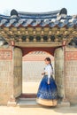 Beautiful Korean woman dressed Hanbok passing the traditional door in palace. Royalty Free Stock Photo