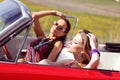 Beautiful ladies with sun glasses posing in a vintage car in a sunny day spring summer