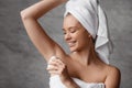 Beautiful lady applying roller deodorant to armpit zone, using antiperspirant for underarms for sweat protection Royalty Free Stock Photo