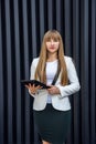 Beautiful lady in business suit holding tablet and posing on abstract background Royalty Free Stock Photo