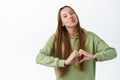 Beautiful lady in hoodie kiss and show heart sign, I love you gesture, standing romantic and cute against white