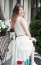 Beautiful lady with long hair in light dress on bike posing at city street near basket of flowers Royalty Free Stock Photo