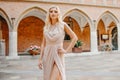 Beautiful lady in luxurious pink ballroom dress. Blond walking along the old castle. The blonde looks at the camera and travels