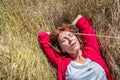 Beautiful lady lying down in dry summer field to enjoy sun