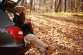 Beautiful lady sitting in open car trunk and drink tea or coffee Royalty Free Stock Photo