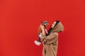 Beautiful lady standing on a red background with a cute dog breed biewer terrier in her arms and smiling. Woman with pet in her Royalty Free Stock Photo