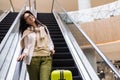 Beautiful lady tourist going down with baggage on escalator at terminal of international airport Royalty Free Stock Photo