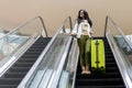 Beautiful lady tourist going down with baggage on escalator at terminal of international airport Royalty Free Stock Photo