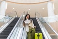 Beautiful lady tourist going down with baggage on escalator at terminal of international airport Royalty Free Stock Photo