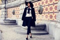 Beautiful ladylike woman in coat and felt hat posing at park