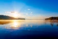 Beautiful lake view in morning fog with mystic mountains and trees as leftovers of a mole in gold, purple - blue tones. Royalty Free Stock Photo