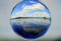 Beautiful lake, white clouds and blue sky captured through a crystal lens ball Royalty Free Stock Photo