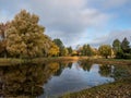 Beautiful landscape of autumn scenery with lake, spur trees and vegetation in yellow, orange and warm toned colors with Royalty Free Stock Photo