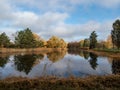 Beautiful landscape of autumn scenery with big lake, spur trees, trees and vegetation in yellow, orange and warm toned colors with Royalty Free Stock Photo