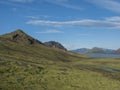 Beautiful landscape of blue Alftavatn lake and river with snow covered mountains and green hills and blue sky background