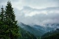 Beautiful landscape with clouds over the tops of the mountains and forest in the fog Royalty Free Stock Photo