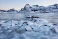 Beautiful landscape cracking ice, frozen sea coast with mountain ridge background at sunrise in winter season, Lofoten Islands, Royalty Free Stock Photo