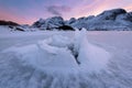 Beautiful landscape cracking ice, frozen sea coast with mountain ridge background at sunset in Lofoten Islands, winter season, Royalty Free Stock Photo