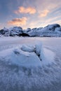 Beautiful landscape cracking ice, frozen sea coast with mountain ridge background at sunset in Lofoten Islands, winter season, Royalty Free Stock Photo