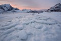 Beautiful landscape cracking ice, frozen sea coast with mountain ridge background at sunset in winter season, Lofoten Islands, Royalty Free Stock Photo