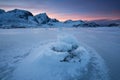 Beautiful landscape cracking ice, frozen sea coast with mountain ridge background at sunset in winter season, Lofoten Islands, Royalty Free Stock Photo