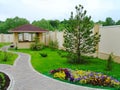 Beautiful landscape design in a private yard. Colorful flowers, green grass and trees. Cosy barbeque house / grill house. Beautifu