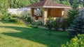 Beautiful landscape design in a private yard. Colorful flowers, green grass and trees. Cosy barbeque house, grill house.