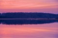 Beautiful landscape of a forest lake with the reflection of the forest in the water. Sunset in the winter season Royalty Free Stock Photo