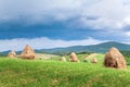 Haystacks on mountain pasture n the background of stormy sky and mountain range. Royalty Free Stock Photo