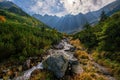 Beautiful landscape with high mountains with illuminated peaks, stones in mountain creek, blue sky Royalty Free Stock Photo