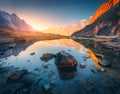 Mountains with illuminated peaks, stones in mountain lake at sunset Royalty Free Stock Photo