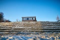 Beautiful landscape with a house on a cliff and a stone wall and fence in winter with snow and sun during sunset or Royalty Free Stock Photo